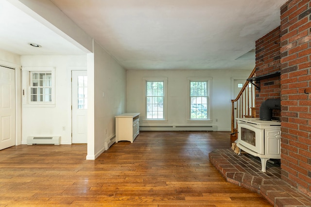 entrance foyer featuring a wood stove, a baseboard heating unit, wood-type flooring, and brick wall