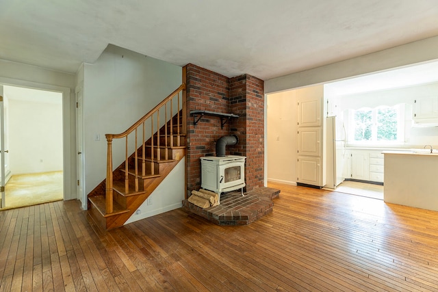 staircase with hardwood / wood-style floors, a wood stove, sink, and brick wall