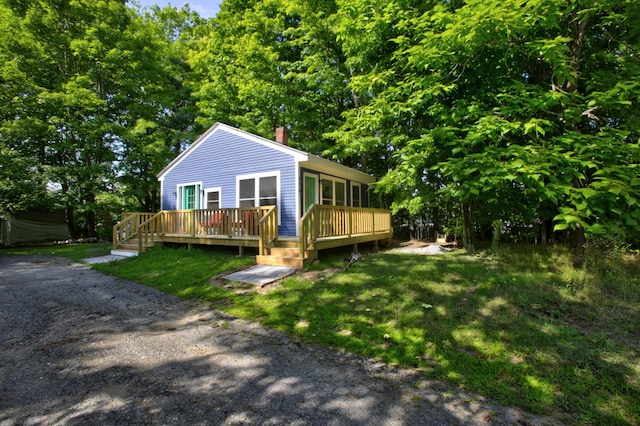 view of front of property with a chimney, a front lawn, and a wooden deck