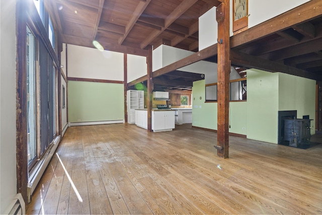 4 Wilson St, Topsham, ME 04086 - unfurnished living room featuring a baseboard heating unit, a wood stove, hardwood / wood-style flooring, a baseboard radiator, and a wooden ceiling with exposed beams