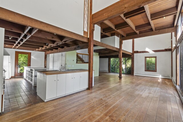 4 Wilson St, Topsham, ME 04086 - kitchen with a baseboard radiator, freestanding refrigerator, white cabinetry, hardwood / wood-style floors, and a wood ceiling with exposed beams
