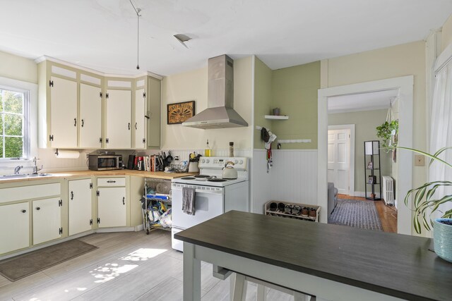 4 Wilson St, Topsham, ME 04086 - kitchen featuring white electric stove, wall chimney range hood, stainless steel microwave, radiator heating unit, and light wood-style floors