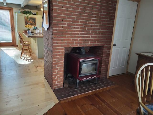 interior details featuring beamed ceiling, wood-type flooring, and a wood stove