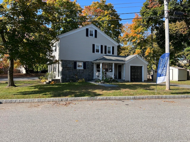 view of front of home with a front yard, a porch, and a garage