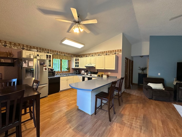 kitchen featuring light hardwood / wood-style flooring, black appliances, lofted ceiling, ceiling fan, and kitchen peninsula