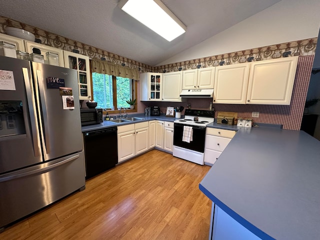 kitchen with lofted ceiling, white cabinets, black appliances, light wood-type flooring, and sink