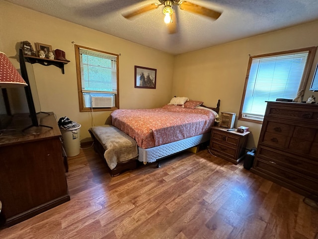 bedroom featuring ceiling fan, a textured ceiling, cooling unit, and hardwood / wood-style floors