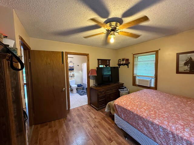 bedroom featuring a textured ceiling, cooling unit, ensuite bathroom, ceiling fan, and wood-type flooring