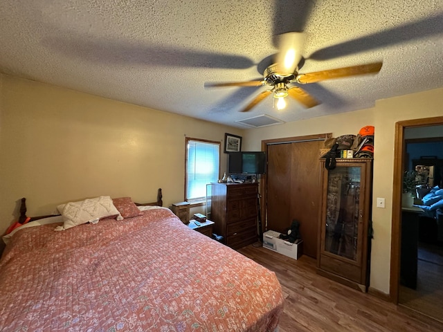 bedroom with ceiling fan, a textured ceiling, and hardwood / wood-style floors