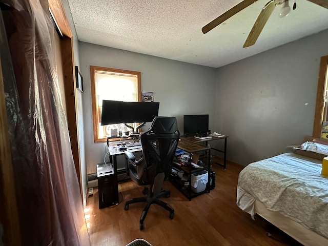 bedroom with ceiling fan, wood-type flooring, and a textured ceiling