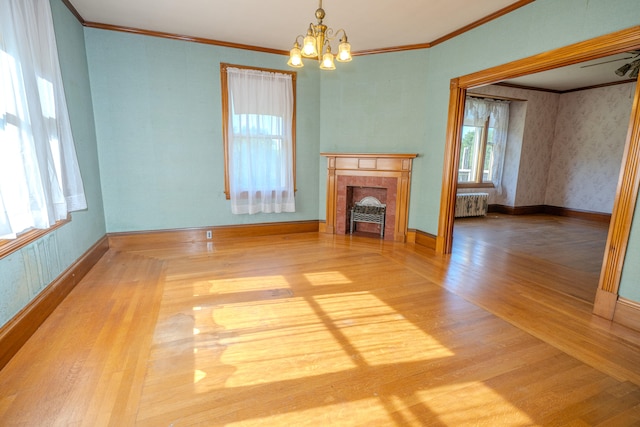 unfurnished living room featuring radiator, a notable chandelier, ornamental molding, and light hardwood / wood-style floors