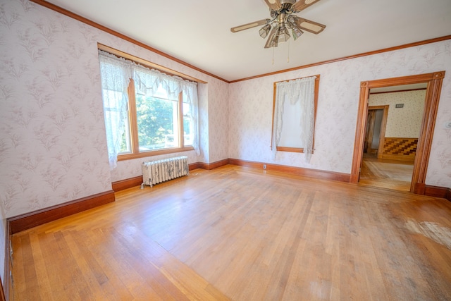 empty room featuring ceiling fan, crown molding, light wood-type flooring, and radiator heating unit