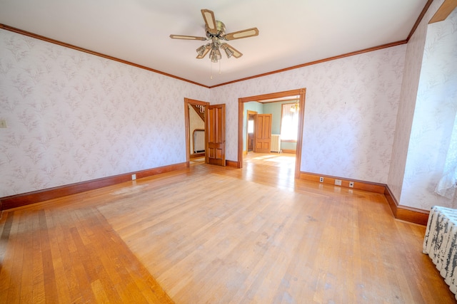 empty room featuring ceiling fan, light hardwood / wood-style flooring, radiator, and crown molding