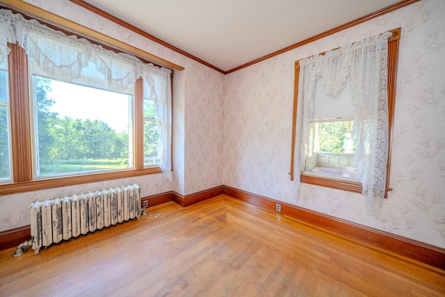 unfurnished room featuring light hardwood / wood-style flooring, radiator, and ornamental molding