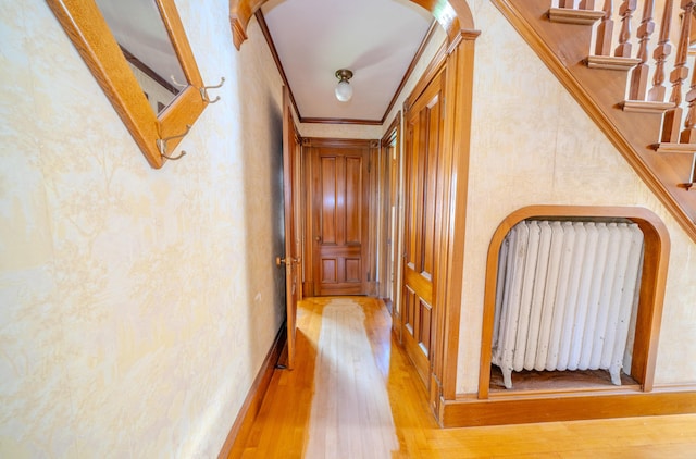 443 S Union Rd, Union, ME 04862 - corridor featuring light wood-style flooring, radiator heating unit, arched walkways, ornamental molding, and stairs