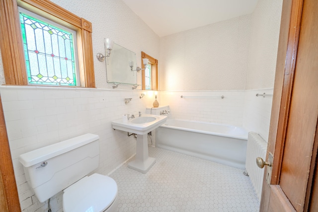 bathroom featuring tile patterned floors, tile walls, radiator, and toilet