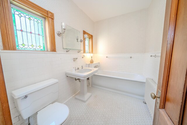 443 S Union Rd, Union, ME 04862 - bathroom with toilet, a bathing tub, a wainscoted wall, tile walls, and radiator heating unit