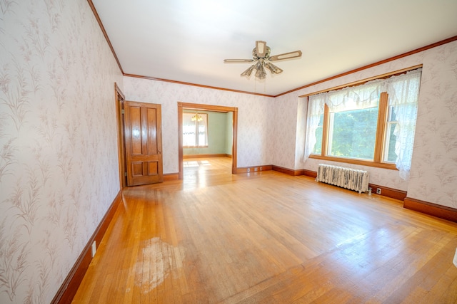 unfurnished room with radiator heating unit, light wood-type flooring, crown molding, and ceiling fan