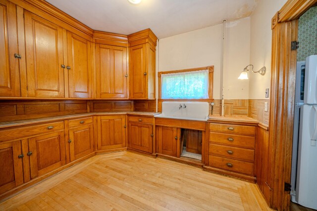 443 S Union Rd, Union, ME 04862 - kitchen featuring freestanding refrigerator, brown cabinetry, light wood finished floors, a wainscoted wall, and light countertops