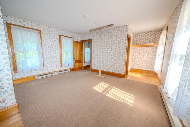 unfurnished bedroom featuring light wood-type flooring and baseboard heating