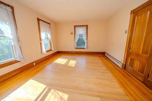 spare room with a baseboard heating unit and light hardwood / wood-style floors