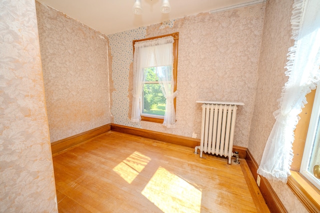 spare room featuring radiator and light hardwood / wood-style flooring