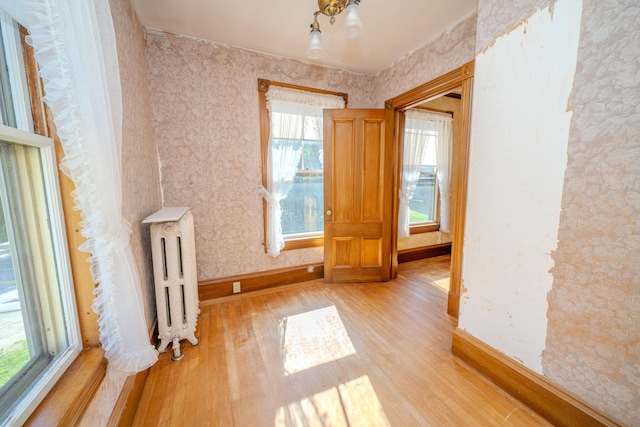 443 S Union Rd, Union, ME 04862 - unfurnished room with light wood-type flooring, a healthy amount of sunlight, radiator heating unit, and wallpapered walls
