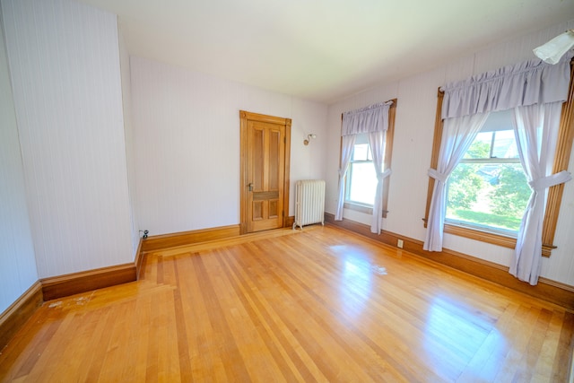 unfurnished room featuring radiator heating unit and light wood-type flooring