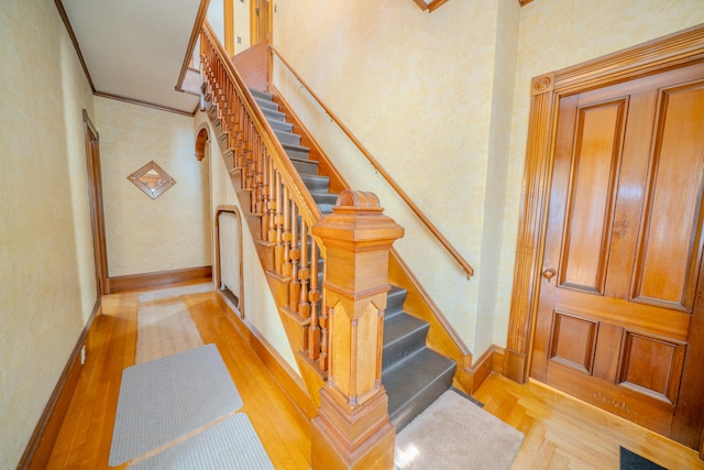 stairs with crown molding and light hardwood / wood-style floors