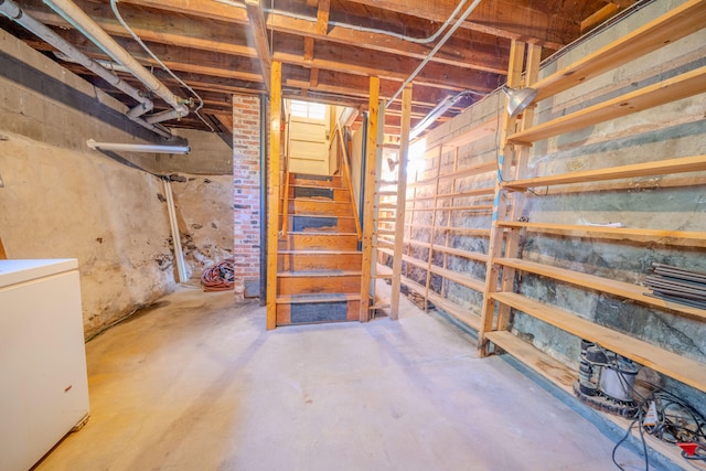 basement featuring washer / dryer and brick wall