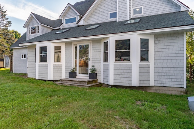 back of house featuring a lawn and roof with shingles