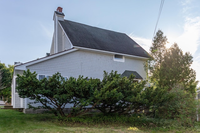 view of side of property with a chimney and a shingled roof