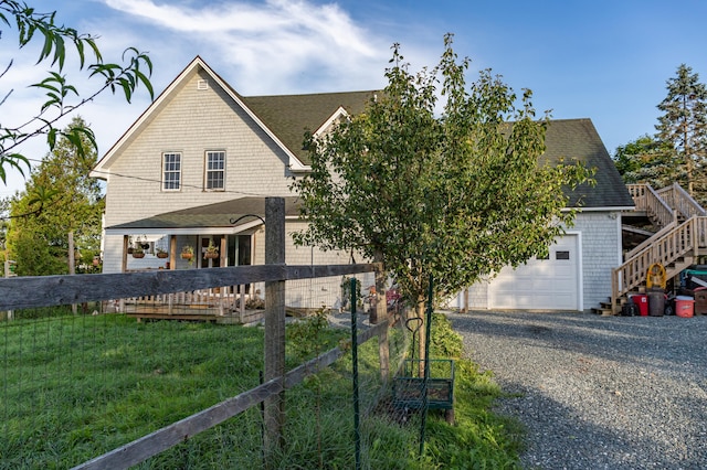 view of front facade with stairway, fence, a garage, and a shingled roof