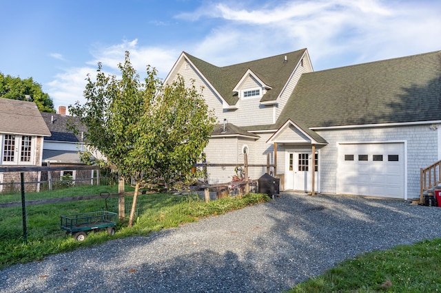 view of front of home with gravel driveway, fence, a garage, and roof with shingles