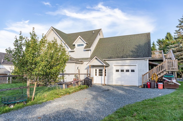 view of front of home with stairs, a shingled roof, gravel driveway, and a garage