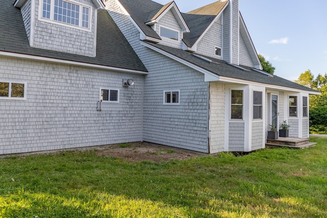 view of home's exterior featuring a yard and a shingled roof