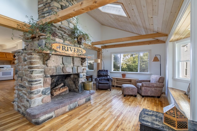 living room featuring a skylight, a fireplace, light hardwood / wood-style flooring, and high vaulted ceiling