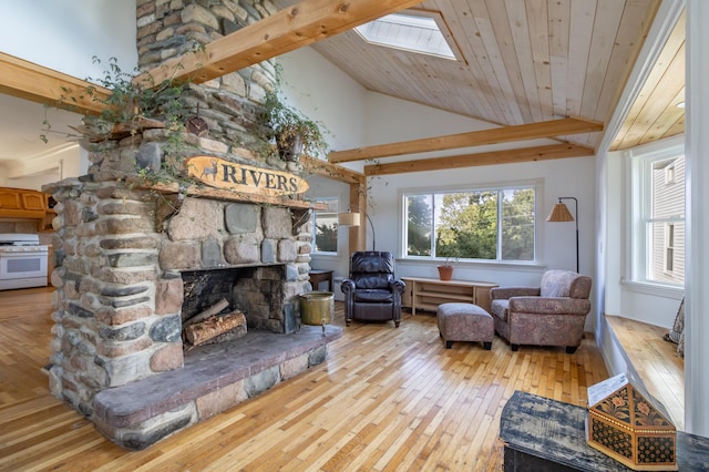 living room featuring high vaulted ceiling, hardwood / wood-style floors, a stone fireplace, a skylight, and wooden ceiling