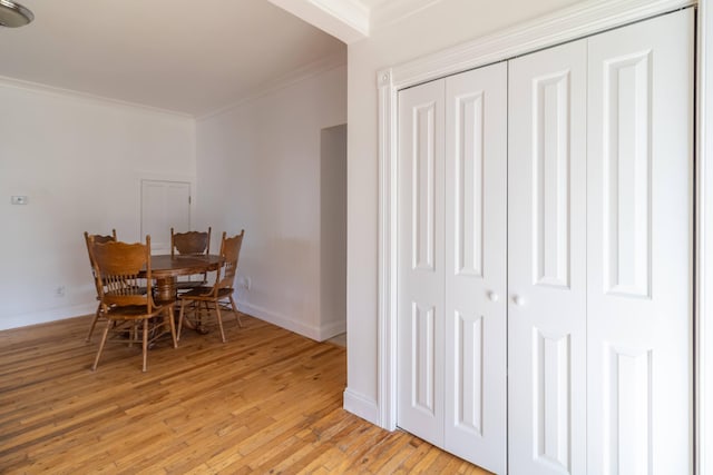 dining space featuring light wood-type flooring, baseboards, and ornamental molding