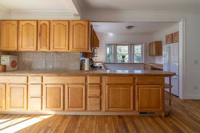 kitchen featuring a peninsula, light wood-style flooring, crown molding, and freestanding refrigerator