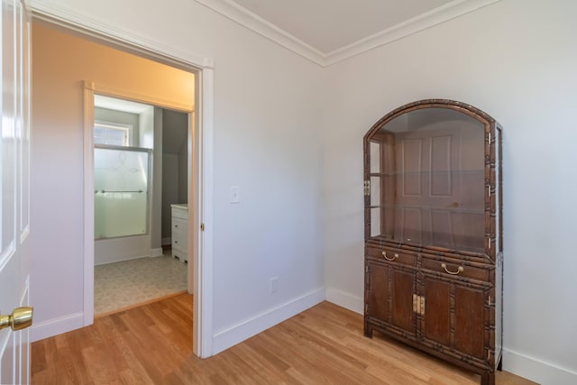 corridor with crown molding, light wood-style floors, and baseboards