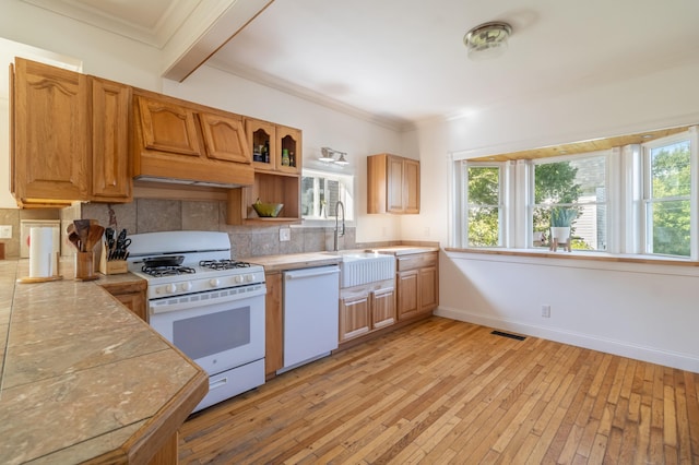 kitchen with white appliances, light wood-type flooring, custom exhaust hood, sink, and tasteful backsplash