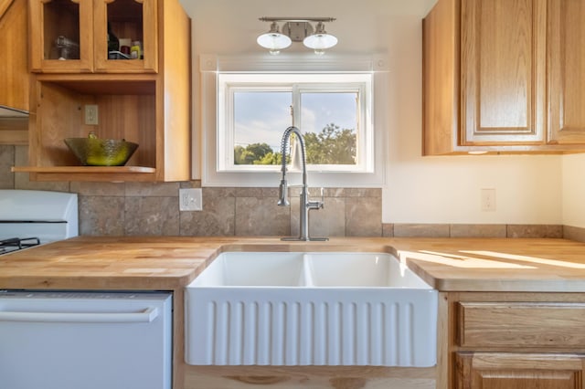 kitchen featuring butcher block countertops, a sink, glass insert cabinets, and white dishwasher