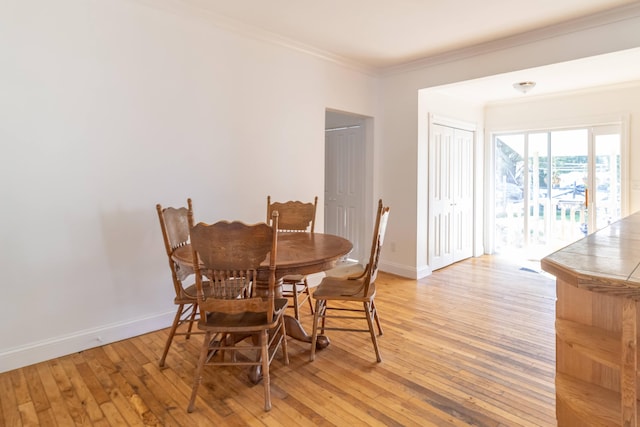 dining room with light wood-type flooring, baseboards, and crown molding
