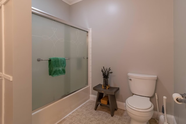 bathroom with toilet, baseboards, and combined bath / shower with glass door