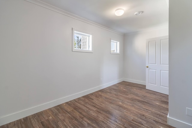 spare room featuring dark wood finished floors, baseboards, and ornamental molding