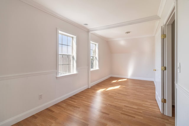 spare room featuring crown molding, light wood-type flooring, and wainscoting