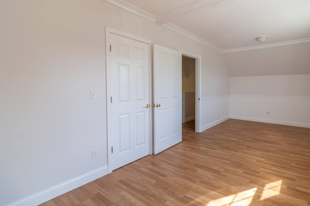 unfurnished bedroom featuring ornamental molding, light wood-type flooring, baseboards, and vaulted ceiling