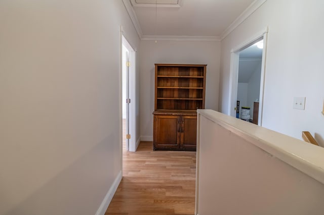 corridor with baseboards, attic access, ornamental molding, and light wood finished floors