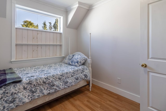 bedroom with crown molding, baseboards, and wood finished floors
